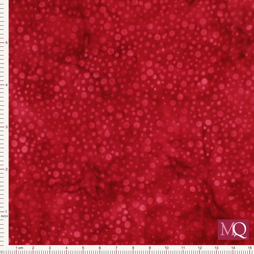 Cotton quilting fabric with tonal batik design featuring small red dots on a darker red background